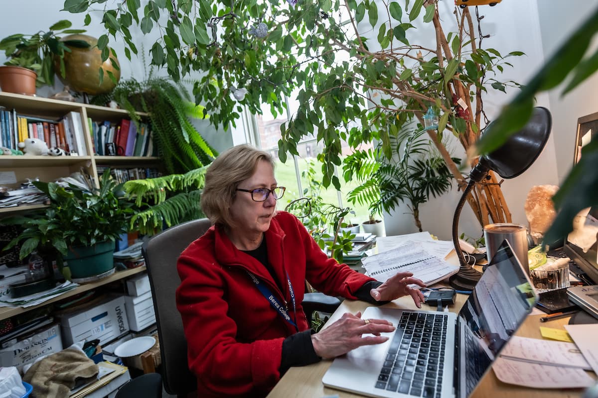 Photo of Dr. Dawn Anderson typing on her computer in her plant-decorated office