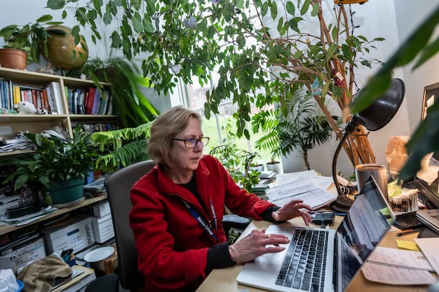 Photo of Dr. Dawn Anderson typing on her computer in her plant-decorated office
