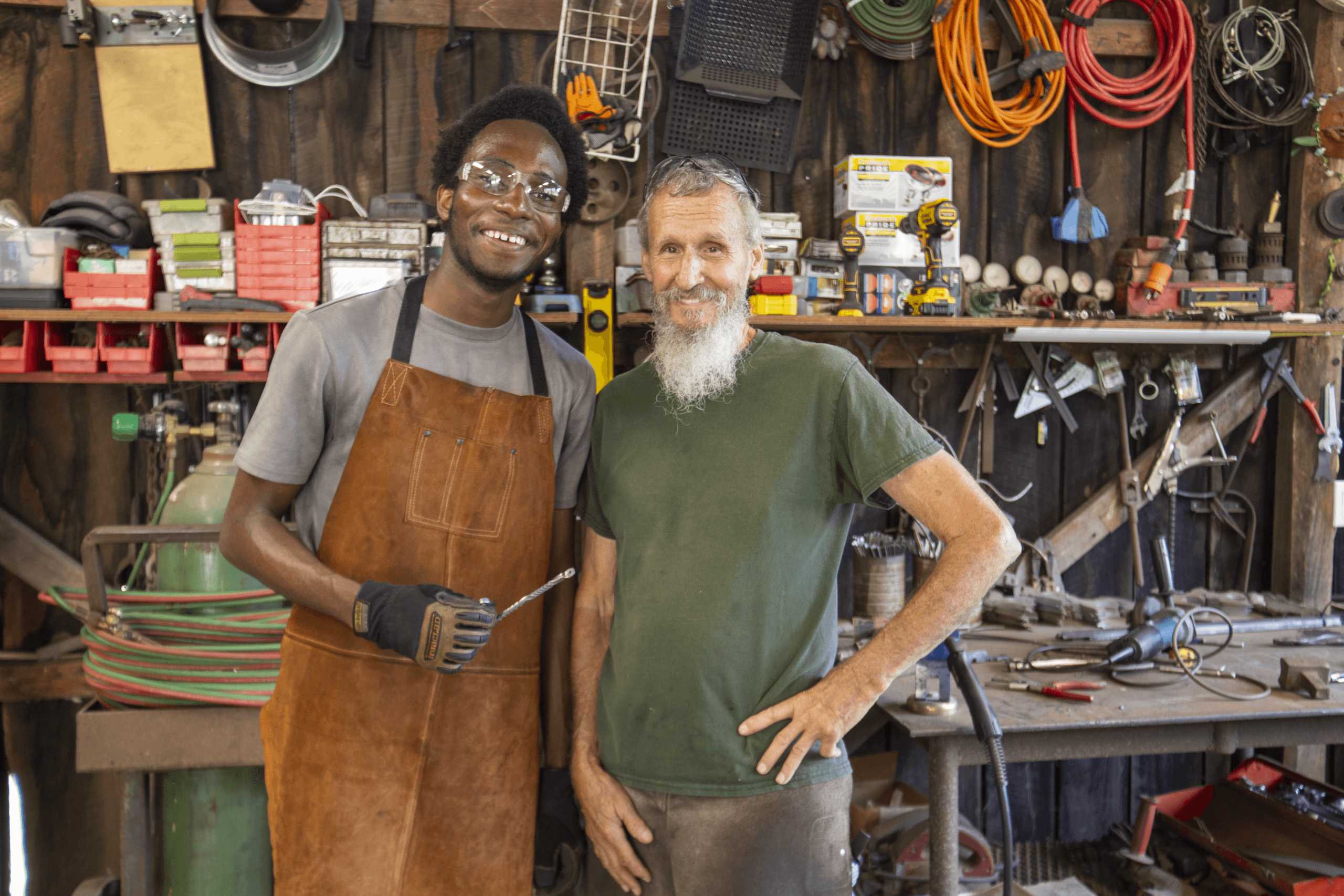 Two men stand alongside each other in a blacksmithing workshop.